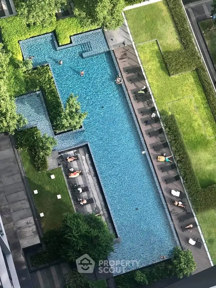 Luxurious rooftop pool with lush greenery and sun loungers in a modern residential complex.