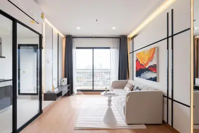 Modern living room with large windows and balcony access, featuring stylish decor and ample natural light.