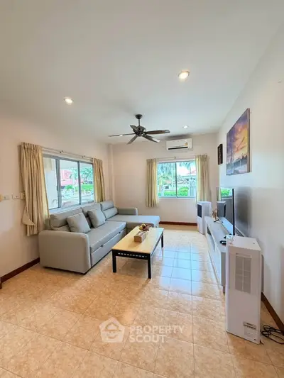 Spacious living room with modern decor and natural light, featuring a comfortable sofa and entertainment setup.