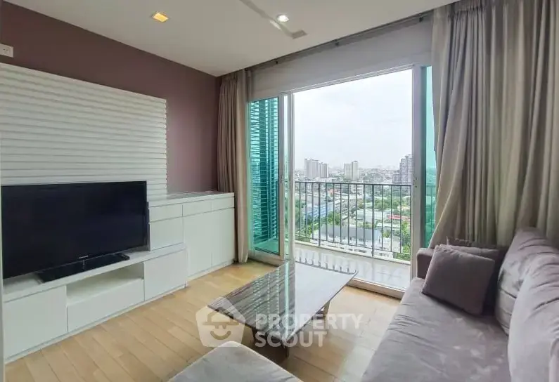 Modern living room with large window offering stunning city view, cozy sofa, and sleek TV setup.