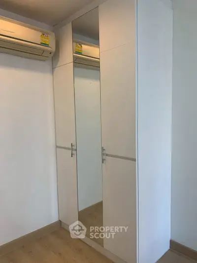 Modern bedroom with mirrored wardrobe and air conditioning unit