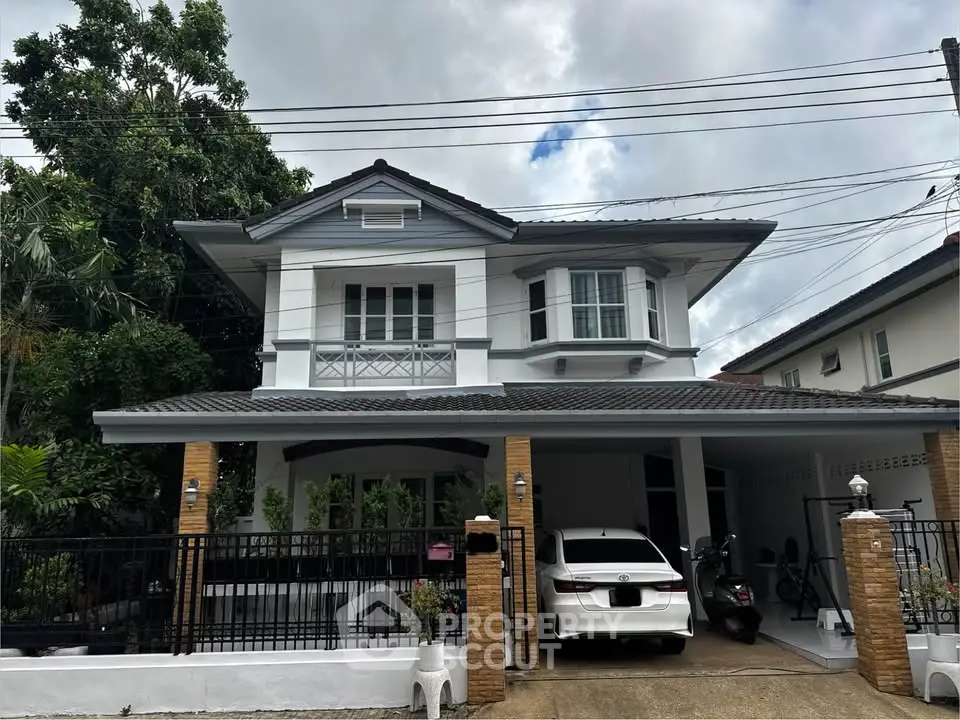 Charming two-story house with carport and lush greenery, perfect for family living.