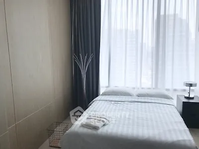 Modern bedroom with large window and city view, featuring minimalist decor and cozy bedding.