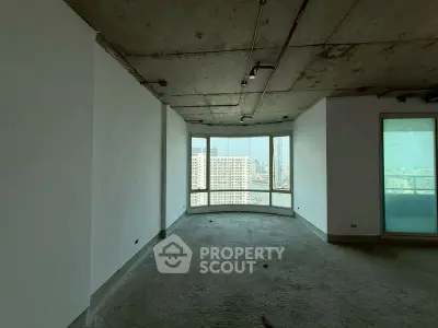 Spacious unfinished apartment with panoramic city view through large windows.