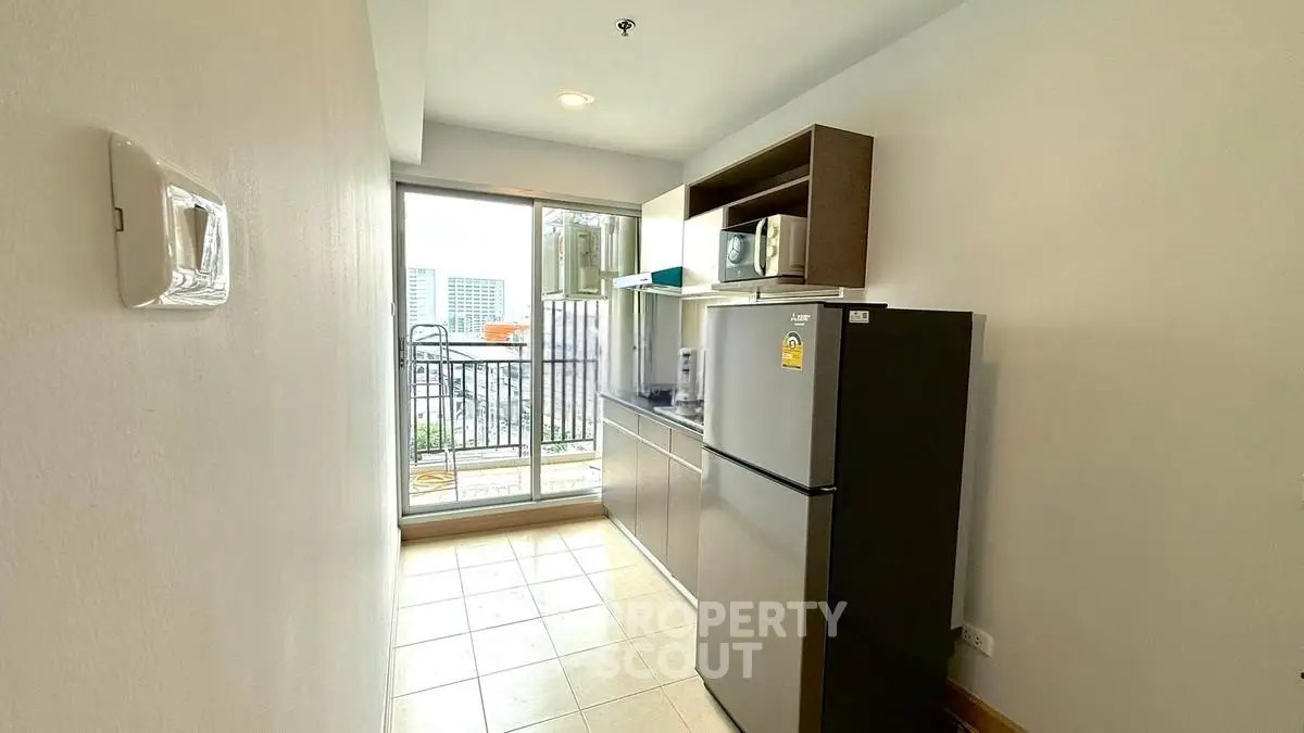 Modern kitchen with sleek appliances and balcony view in urban apartment.