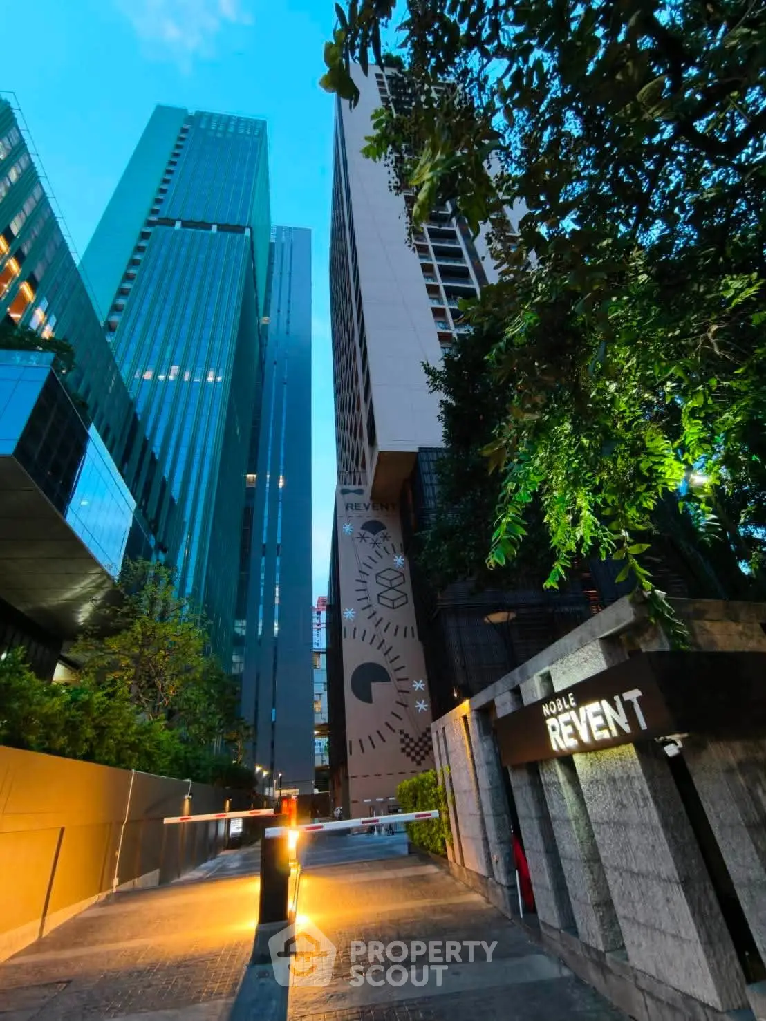 Stunning modern high-rise building entrance with lush greenery and sleek architectural design.