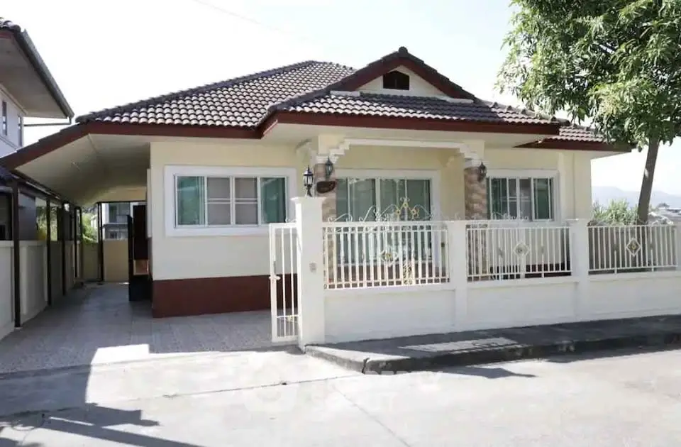 Charming single-story house with tiled roof and gated front yard in a serene neighborhood.