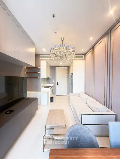 Luxurious modern living room with elegant chandelier and sleek furniture in a high-end apartment.