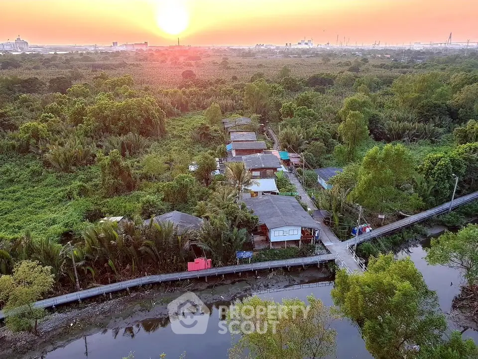 Scenic aerial view of rural homes surrounded by lush greenery at sunset, offering tranquil living environment.