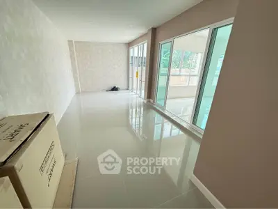 Spacious unfurnished room with large windows and glossy tiled floors, perfect for customization.