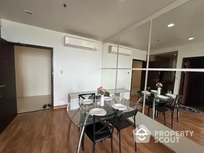 Modern dining area with glass table and mirrored wall in stylish apartment