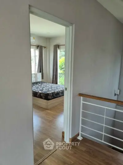 Spacious bedroom with wooden flooring and large windows offering natural light and scenic views.