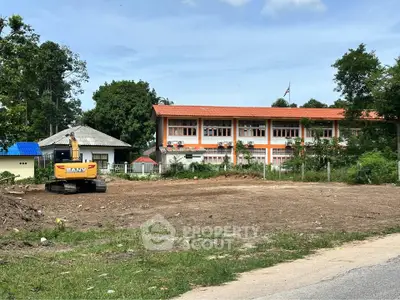 Vacant land with construction equipment near a building, ideal for development.