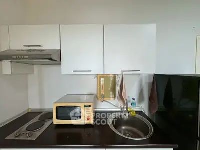 Compact kitchen with microwave, sink, and stovetop in modern apartment