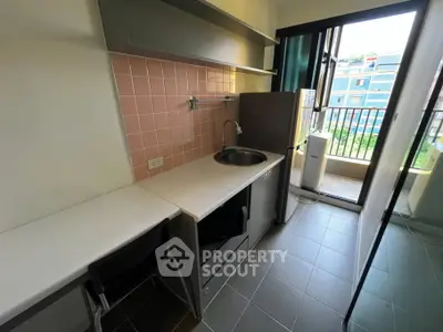 Modern compact kitchen with balcony view in urban apartment