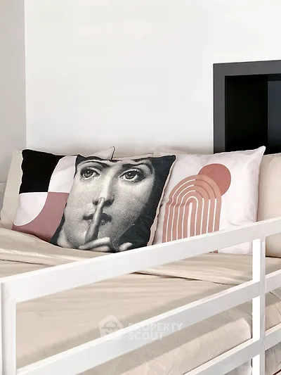 Stylish bedroom with modern art pillows and sleek white bed frame.