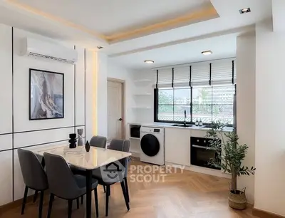 Modern dining area with integrated kitchen, featuring sleek appliances and stylish decor.