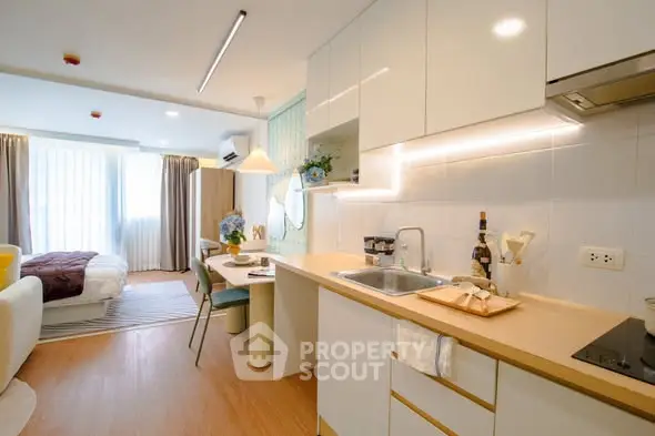 Modern open-plan studio apartment with sleek kitchen and cozy living area, perfect for urban living.