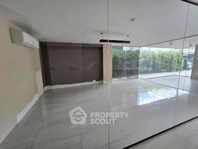 Spacious modern living room with large glass windows and sleek tile flooring.