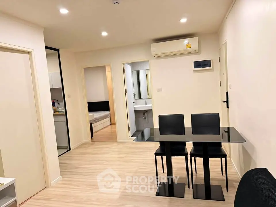 Modern apartment interior with dining area and view into bedroom and bathroom.
