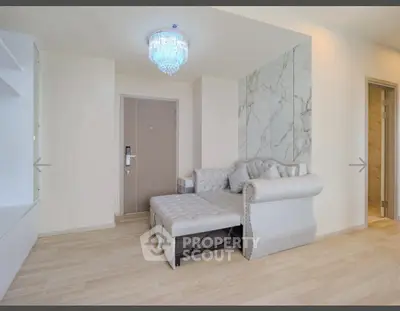 Modern living room with elegant sofa and chandelier, featuring marble accent wall and wooden flooring.