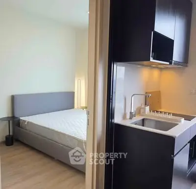 Modern studio apartment with compact kitchen and cozy bedroom area.