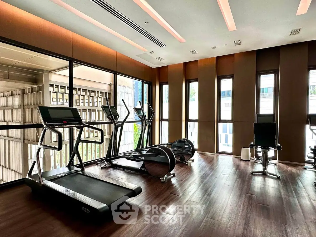 Modern gym with state-of-the-art equipment and large windows in luxury residential building.