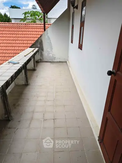 Spacious balcony with tiled flooring and red roof view, perfect for outdoor relaxation.