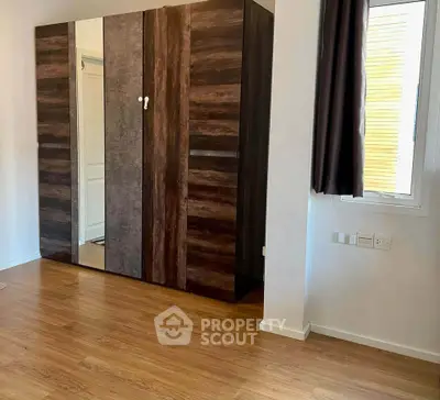 Spacious bedroom with elegant wooden wardrobe and natural light.