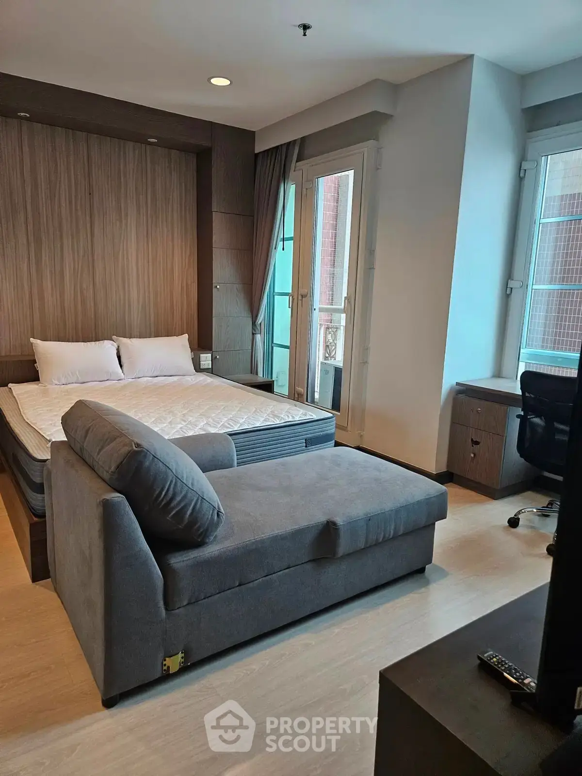 Modern studio apartment with cozy bed and stylish sofa in a bright, well-lit room.