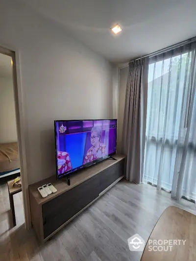 Modern living room with large TV and natural light from window