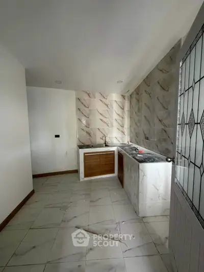 Spacious kitchen with elegant marble tiles and modern cabinetry, perfect for culinary enthusiasts.