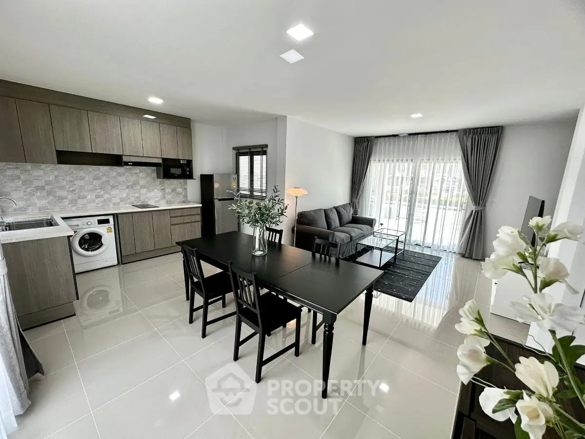 Modern open-plan living room and kitchen with sleek furniture and natural light.