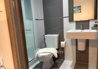 Modern bathroom with sleek design and neutral tones, featuring a shower and contemporary fixtures.