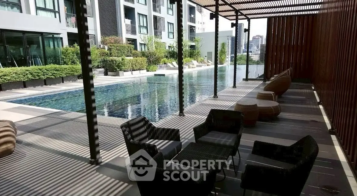 Luxurious poolside area with modern seating and city view in upscale apartment complex.