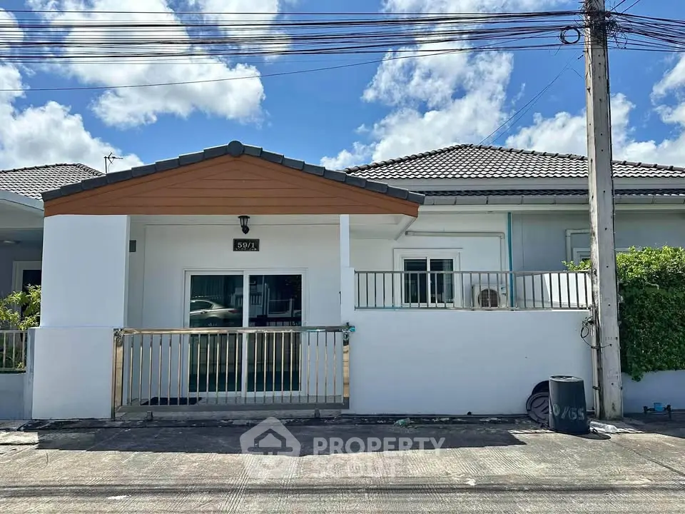 Charming single-story house with modern facade and gated entrance under a clear blue sky.