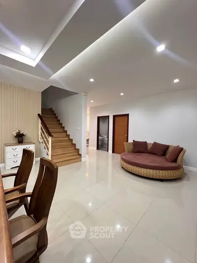 Spacious modern living room with elegant staircase and stylish furniture.