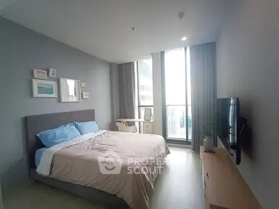 Modern bedroom with large window and city view, featuring stylish decor and comfortable furnishings.