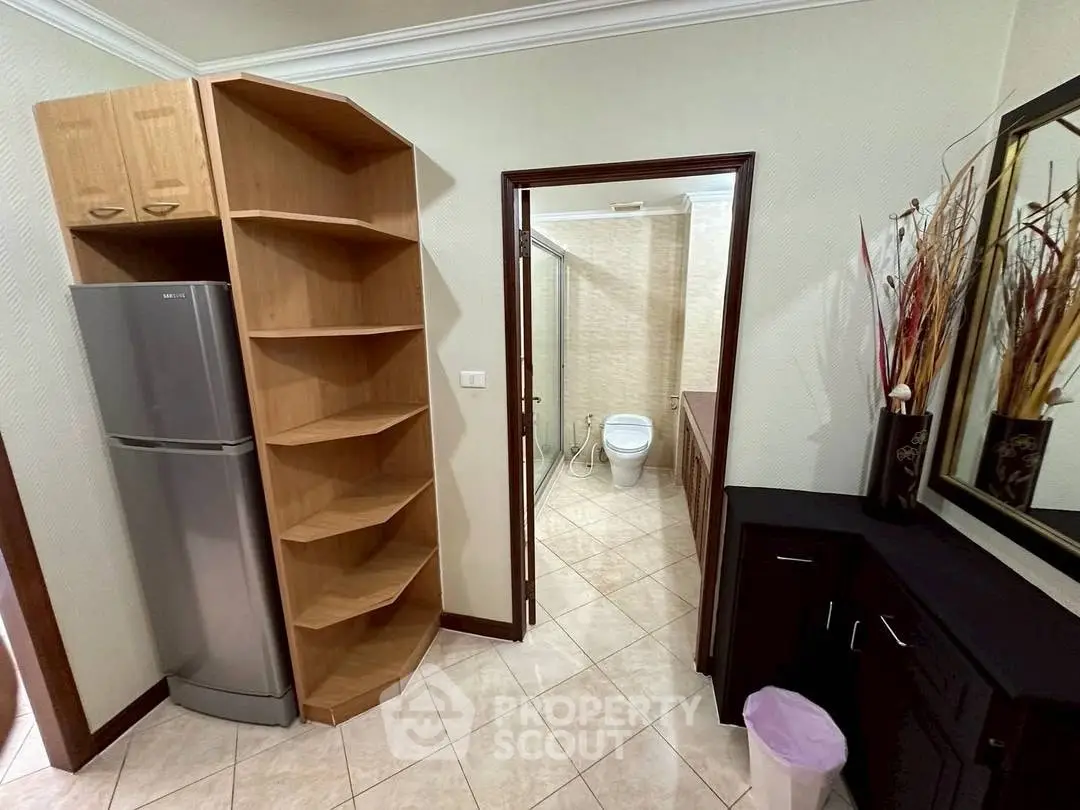 Modern interior with fridge, shelving, and bathroom view in stylish apartment.