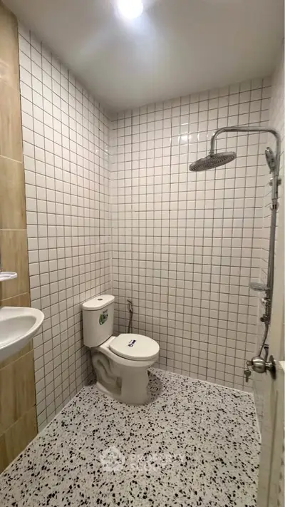 Modern minimalist bathroom with white tiles and rainfall showerhead.