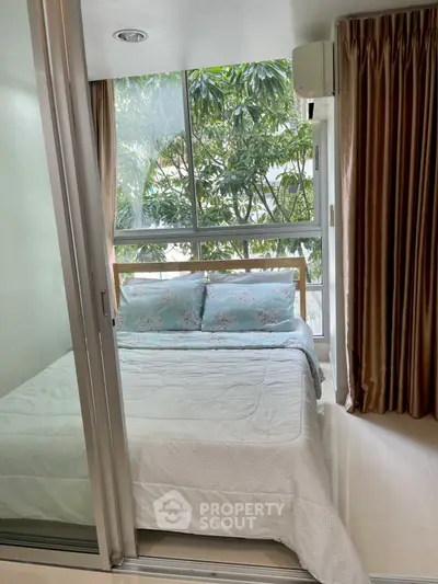 Cozy bedroom with large window and lush green view, featuring elegant curtains and a comfortable bed.