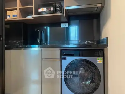 Modern kitchen with sleek appliances and stylish cabinetry in compact layout.