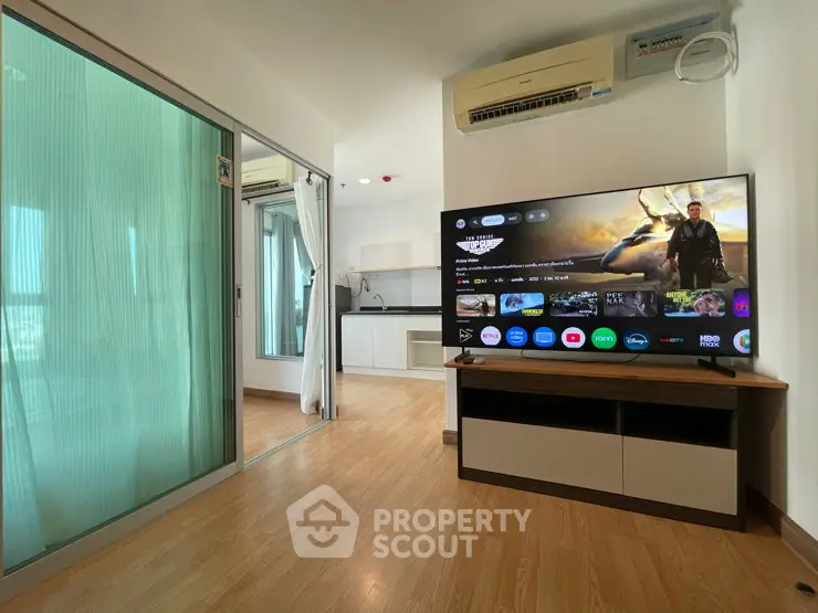 Modern living room with sleek TV and open kitchen in a stylish apartment.