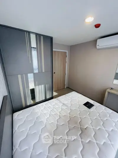 Modern bedroom with sleek wardrobe and air conditioning, featuring a comfortable mattress and stylish decor.