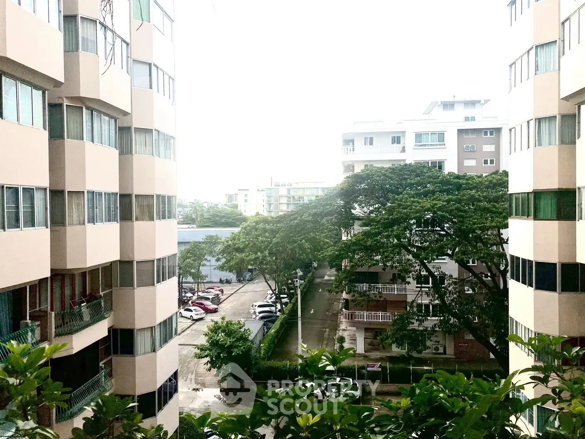 Scenic view of modern apartment buildings with lush greenery and parking area.