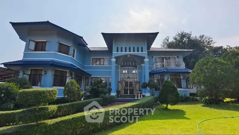 Stunning blue two-story house with lush garden and elegant entrance