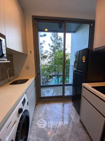 Modern kitchen with sleek appliances and balcony view, perfect for urban living.