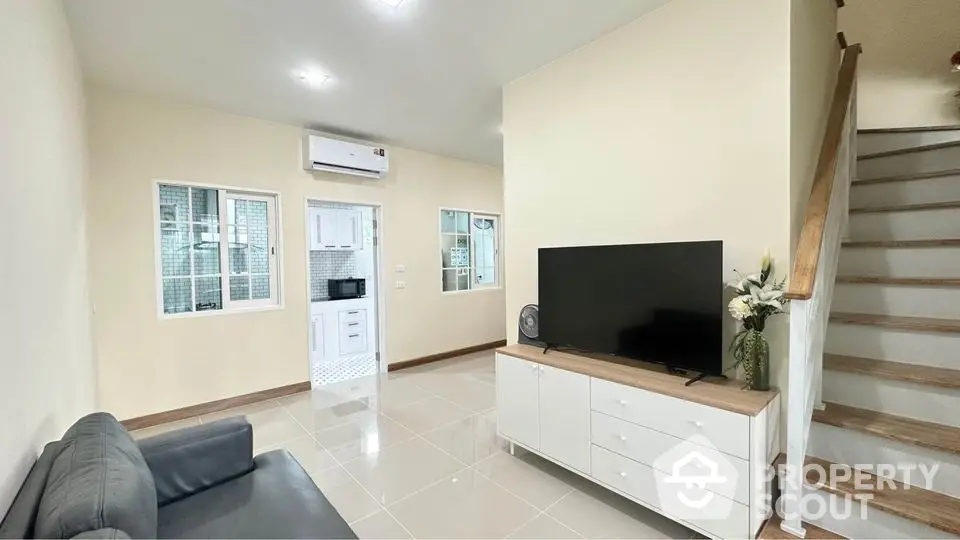 Modern living room with sleek TV setup and adjacent kitchen view