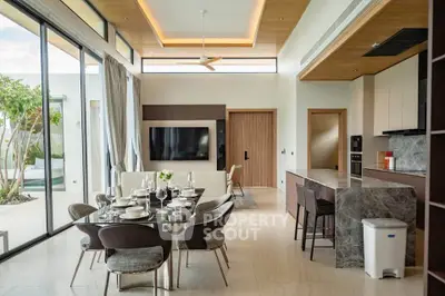 Luxurious open-plan living and dining area with modern kitchen and pool view, perfect for entertaining.