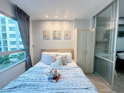 Cozy bedroom with modern decor and large window offering natural light in urban apartment.